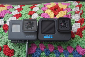 Comparison of my older GoPro Hero 5 Black and Hero 10 Black cameras side-by-side. The Hero 5's battery door at the bottom is open here, with the battery itself flipped around and sticking out from the camera slightly