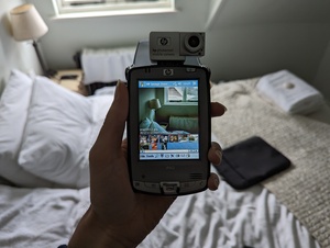 HP iPAQ hx2490b with the Photosmart SDIO camera attached. The iPAQ is turned on and opened with the 'HP Image Zone application, displaying a photo taken with the camera, along with a two-row filmstrip below that displaying thumbnails of other photos in the device's library