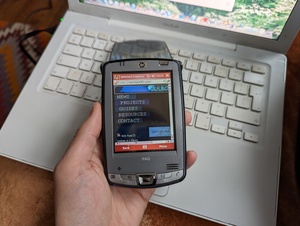 HP iPAQ hx2490b displaying razorback95.com using the version of Internet Explorer included with Windows Mobile 5.0. The 2009 13 inch MacBook providing the Internet connection is visible behind it
