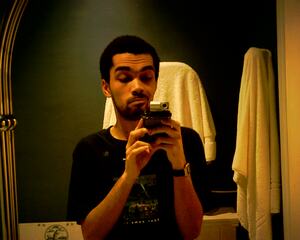 Selfie of me taken with the Photosmart camera in a bathroom mirror. In the photo I'm smiling and looking below towards the screen of the HP iPAQ