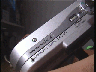 Closeup photo showing the top of the Cybershot camera itself, with the model number, power button and mode dial